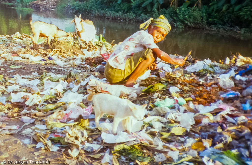 Eine ältere Frau durchsucht einen Abfallberg 1986 in Lombok, Indonesien nach Verwertbaren