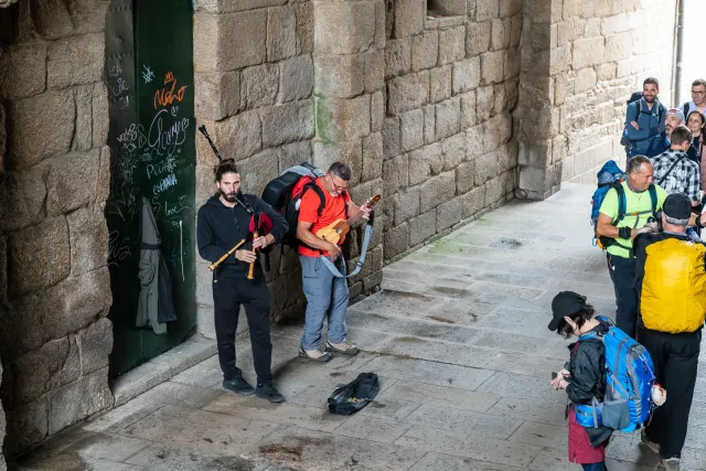 Pilger freuen sich über den Dudelsack-Straßenmusiker, der freut sich gar nicht.