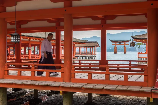 Ein Shintō-Mönch in den langen Säulengängen zum Itsukushima-Schrein