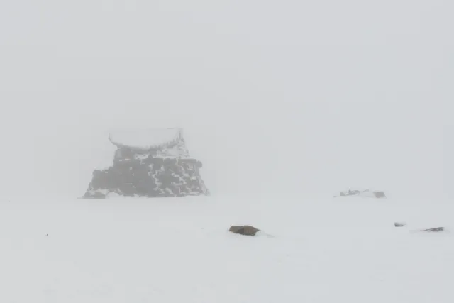 The summit hut appears in the fog