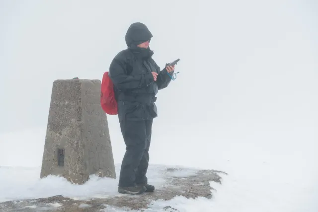 Karin geocaching at the marker rock at the top of Ben Nevis.