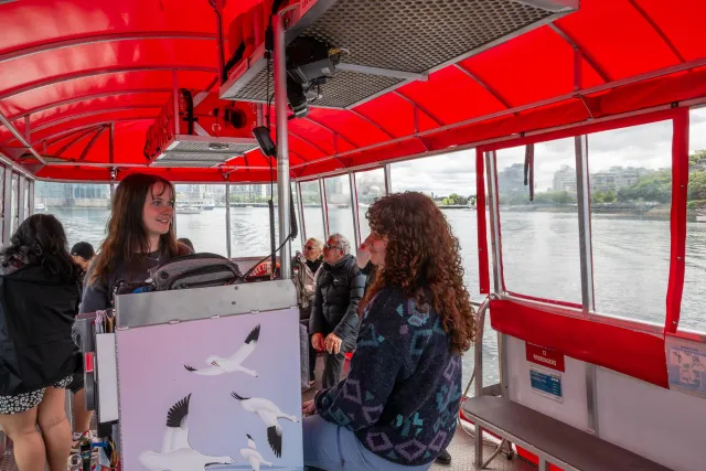 Mit dem Wassertaxi über den Creek – zwei junge Frauen steuern das Boot sicher ans Ufer